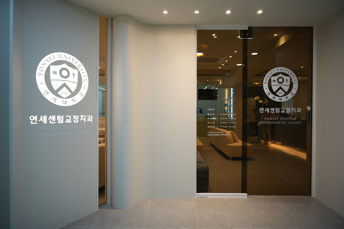 연세센텀치과 입구 전경 사진 - 연세대학교 마크와 진료시간 안내가 있는 유리문 입구